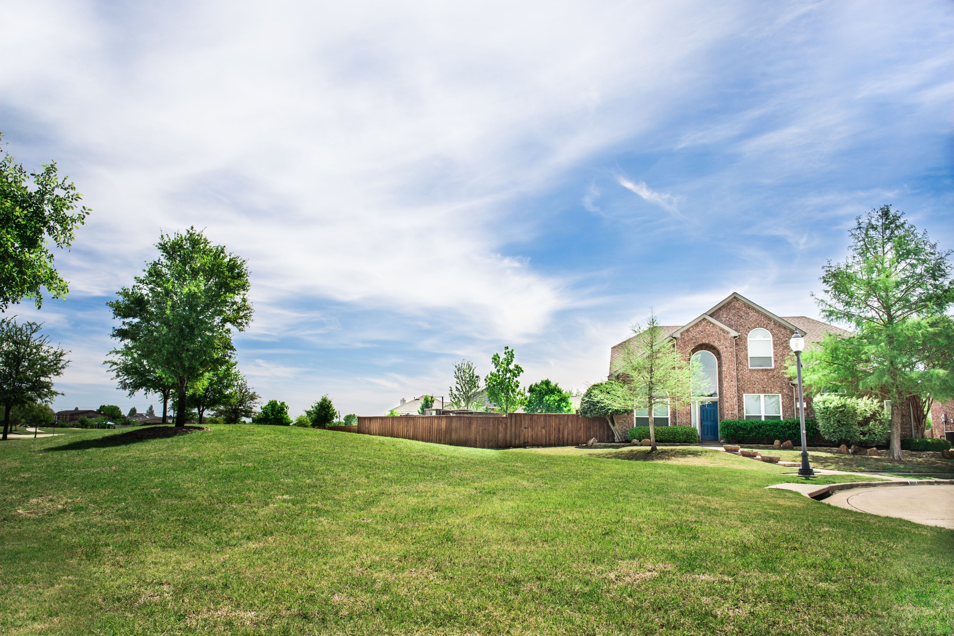 Pretty suburban home with green lawn, trees and blue skies